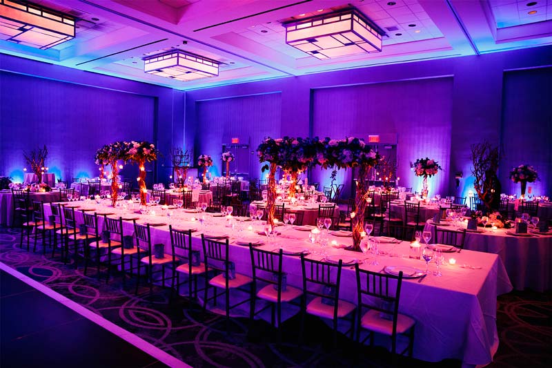 Tables dressées et décorées avec des lumières violettes et roses.